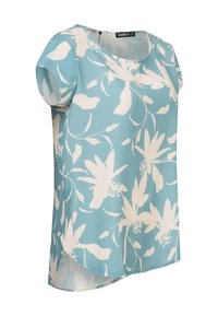 Blouse bleu clair en tissu léger, présentant un motif floral blanc, des manches courtes et un col arrondi avec un ourlet incurvé.
