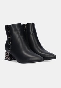 Botas ankle negras de cuero liso, con punta afilada, cremallera lateral y tres botones decorativos en el talón exterior.