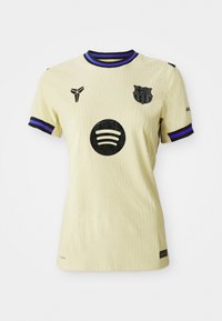 Gul fotbollströja med en strukturerad design, svarta accenter och lila randig krage och ärmar. Har en logotyp på framsidan.