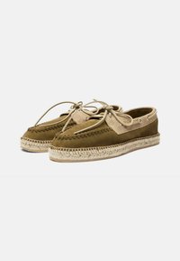 Zapatos de ante marrón con acentos en beige, puntera redonda, diseño con cordones y suela de yute trenzado. Presenta costuras decorativas en la parte superior.