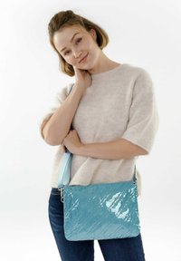 Bolso de hombro azul de charol con acabado texturizado y correa ajustable, que presenta una forma rectangular y un sutil detalle de costura diagonal.