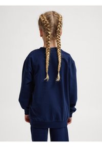 Felpa blu navy con collo rotondo, vestibilità comoda e maniche lunghe, vista da dietro. Presenta capelli intrecciati. Design semplice, senza fantasie.