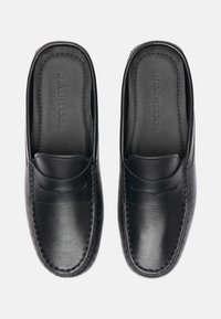Schwarze Leder Slipper mit glatter Oberfläche, ausgestattet mit einer Stichverzierung und einem dezenten Frontband-Design. Innen etikettiert "MADE IN ITALY."