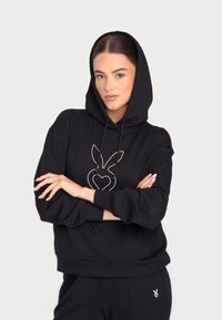 Hanorac negru cu glugă, având un logo alb la mijloc. Material moale, croială lejeră și manșete ribbate. Asortat cu pantaloni jogger corespunzători.