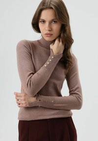 Lila coltrui met lange mouwen, met gouden knoopaccenten op de manchetten. Gemaakt van zachte, gestructureerde garen. Casual pasvorm.