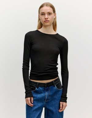 Zwarte langärmmode met een aansluitende pasvorm, ribbelstructuur, ronde halslijn en duimgaten in de manchetten, gecombineerd met hoog-waist blauwe denim jeans.