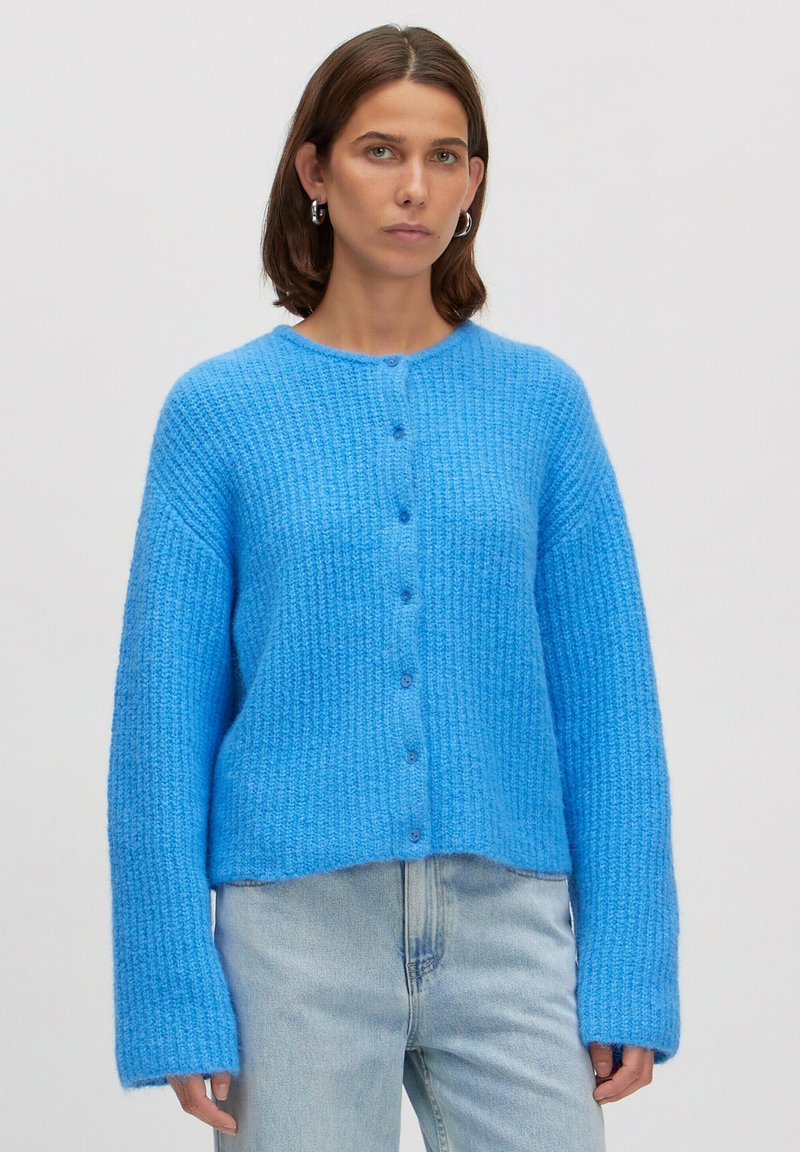 Felblau geribde cardigan met een ronde hals, lange mouwen en knoopsluiting. Zachte textuur, kort model, perfect te combineren met lichte spijkerbroeken.