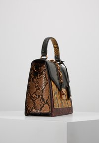 Bolso estructurado que presenta una mezcla de patrones de estampado de serpiente en marrón, amarillo y negro. Acentuado con un candado dorado y una correa de cadena.