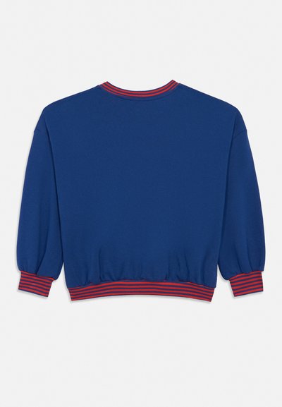 Niebieska bluza z długim rękawem z czerwono-niebieskimi prążkowanymi ściągaczami przy mankietach, dole i dekolcie, widziana od tyłu na białym tle.