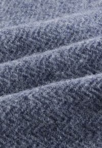 Wollstoff in hellblau-grau, mit einer weichen, strukturierten Oberfläche, einem feinen, flauschigen Aussehen und einem dezenten Fischgrätmuster.