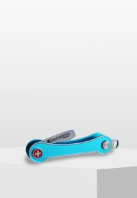 Multiverktyg nyckelring med ett blått aluminiumhus, silvriga accenter och en röd korslogotyp. Har en vikbar design för kompakt förvaring.