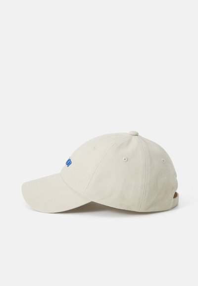 Beige baseball cap med buet skygge, justerbar rem, brodert blå logo og ventilasjonsåpninger på toppen. Mykt bomullsmateriale.