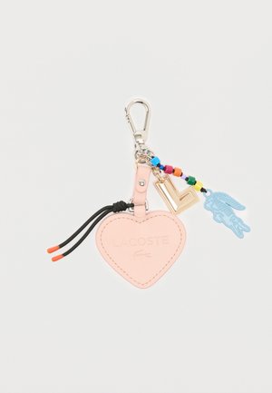 Porte-clés rose en forme de cœur avec logo "Lacoste" en relief, perles colorées, breloque dorée en forme de "L", breloque crocodile bleue et attache clip en argent.