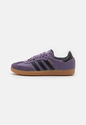 Purple leather sneakers with black stripes, gum rubber sole, rounded toe, and low-top design. Features "Samba" branding. Smooth texture.