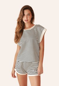 Gestreiftes Baumwolle-Loungewear-Set bestehend aus einem lockeren kurzärmeligen Oberteil und passenden Shorts in Weiß mit schwarzen Streifen, das einen lässigen Schnitt und eine weiche Textur bietet.
