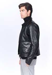 Chaqueta bomber de cuero negro con cierre de cremallera en el frente, puños acanalados y un acabado suave. Presenta dos bolsillos frontales con solapas y un cuello clásico.