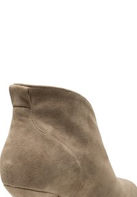Beżowe zamszowe botki za kostkę o gładkiej fakturze, z okrągłym noskiem i niskim obcasem. Charakteryzują się smukłą sylwetką i dekoracyjnym przeszyciem wzdłuż krawędzi.