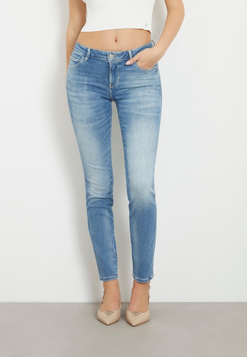 Ljusblå smala jeans med en blekt tvätt, med fem fickor och knäppning, i kombination med nude spetsiga klackar.