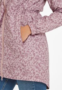 Lightweight pink jacket with a brushstroke pattern, elastic cuffs, and a drawstring waist. Features a zip closure and side pockets.