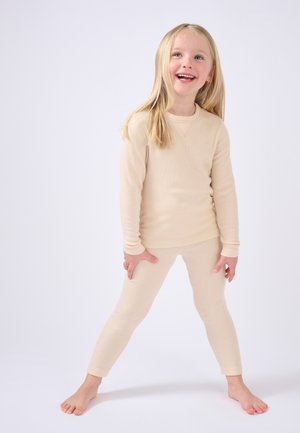 Maglietta beige a maniche lunghe e leggings, texture a coste, design aderente, con scollatura rotonda e polsini aderenti. Nessun motivo o dettaglio aggiuntivo.