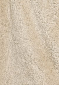 Tessuto di un beige chiaro con una superficie morbida e pelosa, caratterizzato da un aspetto shaggy e da ciocche irregolari e soffici in tutto il materiale.
