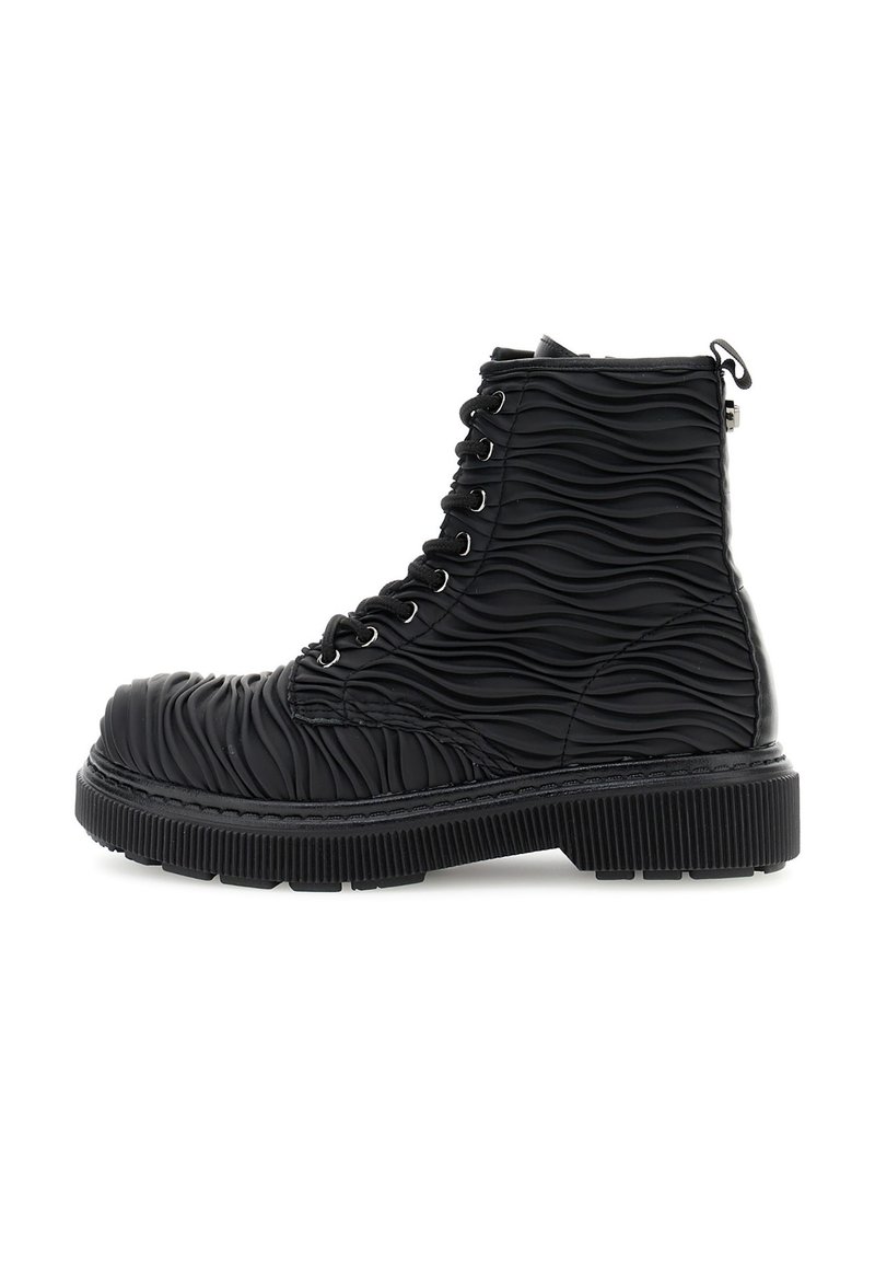 Bota negra con cordones, con una textura estriada y ondulada que cubre toda la parte superior y una suela gruesa y estriada.