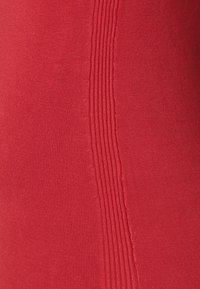 Close-up van rode stof met een gladde tricotstructuur en verticale ribbeldetails aan één kant.