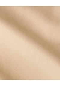 Beżowy materiał o gładkiej, teksturowanej powierzchni, z delikatnym wzorem prążków. Materiał wydaje się lekki i miękki.