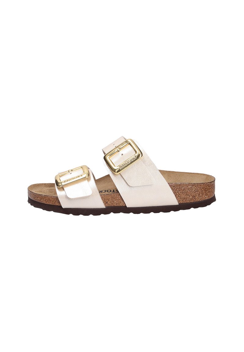 Sandalia de deslizar en cuero beige pálido con dos correas ajustables, hebillas doradas y una plantilla de corcho marrón. Suela de goma texturizada para mayor agarre.