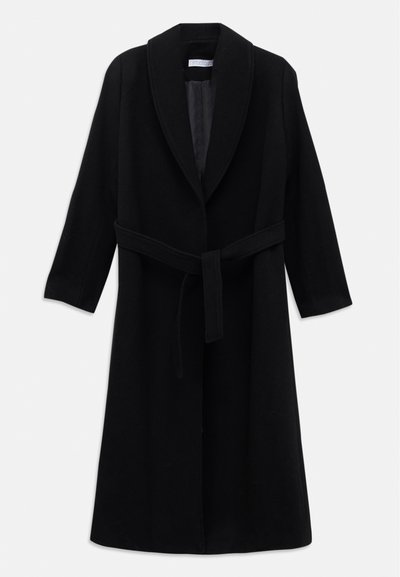 Ilgi melns vilnas mētelis ar šallītes apkakli un jostu, ko piekārtojis uz balta fona.