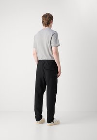 Grå kortermet t-skjorte parret med svarte joggebukser med elastisk midje og baklomme, båret med hvite sneakers.