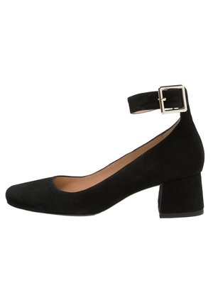 Chaussure pour femme en daim noir avec talon bas carré, bout arrondi et bride de cheville fixée par une boucle argentée.