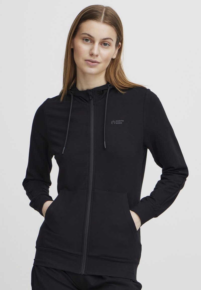 Black zip-up hoodie in soft fabric featuring a drawstring hood, front pockets, and subtle branding on the left chest area.