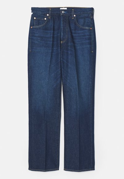 Temno modri jeans s ravnim krojem, ki vključujejo klasično zasnovo s petimi žepi, kontrastno rumeno šivanje in kovinske zakovice.