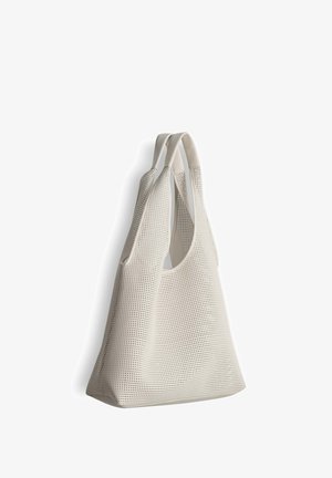 Grand sac fourre-tout blanc perforé avec deux poignées, présenté suspendu sur un fond blanc.