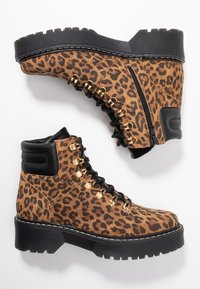 Stivali alla caviglia in stampa leopardata realizzati in suede, con occhielli dorati, lacci neri, suola spessa e una cerniera laterale per una facile vestibilità.