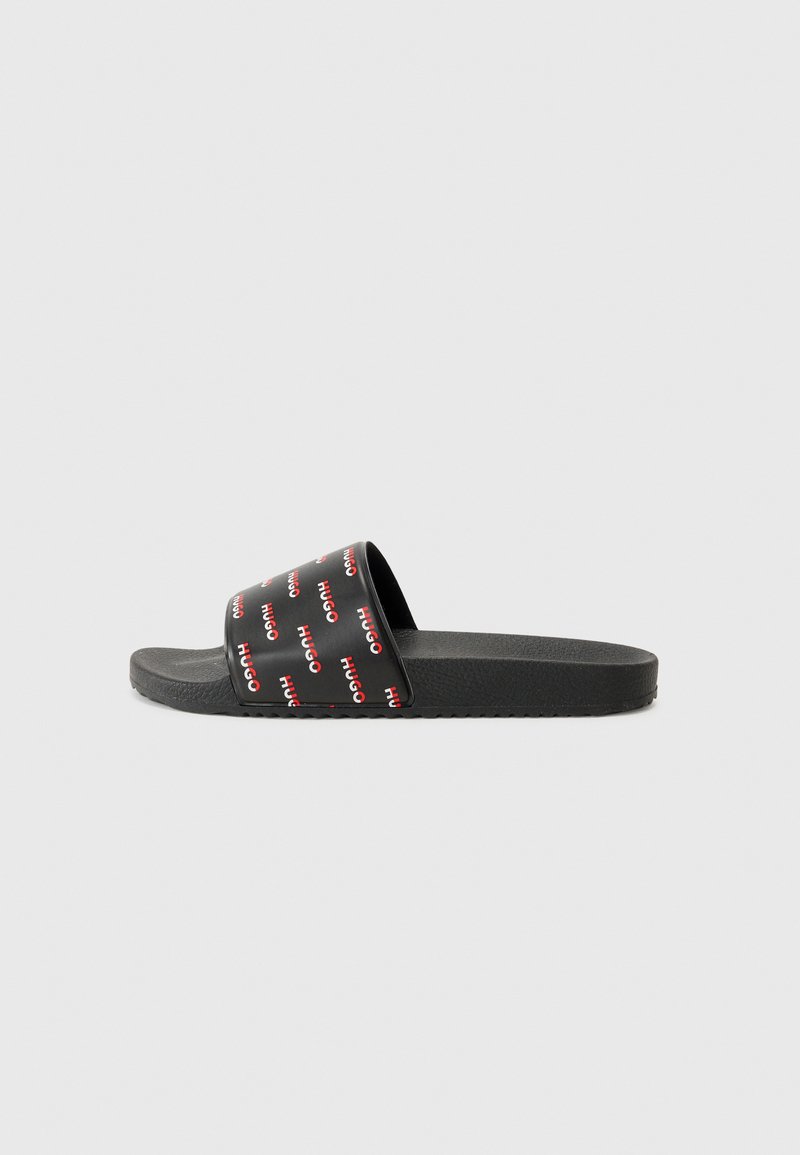Black slide sandal with a wide strap featuring red text repeating "HUGO," textured black sole for grip, minimalistic design.