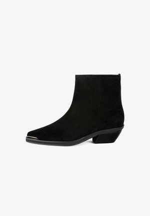 Stivaletto in suede nero con punta a punta, tacco angolare basso e accentuazione metallica sulla punta. Texture liscia e design slanciato.