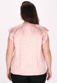 Kortærmet lyserød bluse med leopardmønster. Har flæseærmer og en rund halsudskæring. Glat, letvægtsstof.
