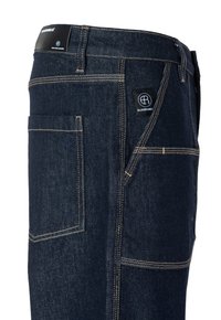 Temno denim hlače z oranžnim šivom, ki imajo zadnji žep in oznako z napisom "Elias Rumel" na pasu, krojene za prilega silhueto.