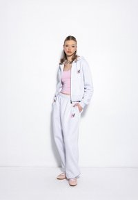 Helle graue Fleece-Haube mit rosa Akzenten, passende graue Sweatpants und rosa Tanktop. Verfügt über ein Logo-Patch und einen Kordelzug an der Taille.