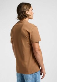 Brun bomullströja med korta ärmar och rundad hals, med en slät yta och avslappnad passform. Minimalistisk design, inga mönster.