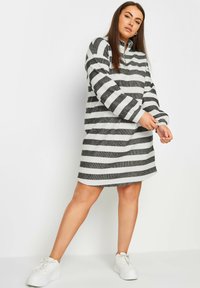 Randig klänning med grå och vita horisontella linjer. Mjuk tyg med en avslappnad passform, med hög krage och långa ärmar.