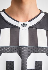 Hallide hallitussärk, millel on valged triibud ja suured valged numbrid. Omab võrgustruktuuri ja kontrastset kraed, millel on väike logo.