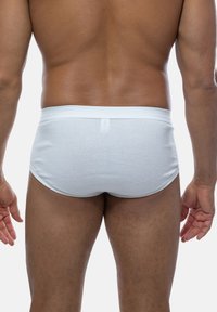 Mutande bianche in cotone viste da dietro, con una cintura morbida e una vestibilità aderente sulla pelle, caratterizzate da una superficie liscia.