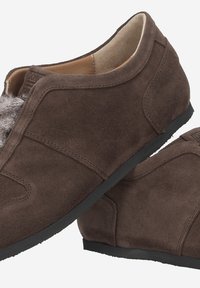 Chaussures en suède marron au design épuré, dotées d'un accent de fourrure douce sur le dessus et d'une semelle en caoutchouc noir. Texture lisse dans l'ensemble.