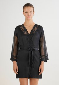 Accappatoio di raso nero con bordo in pizzo floreale sul collo e sulle maniche, con inserti in pizzo trasparente e una cintura in vita per la chiusura.