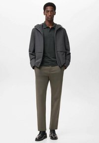 Gray lightweight jacket, dark green polo shirt, and olive trousers. Black shoes. Modern fit and smooth texture throughout.