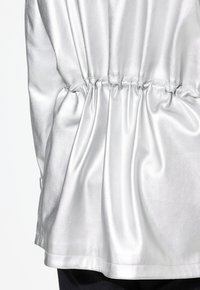 Hopea satiinitoppi, jossa on kootut elastiset yksityiskohdat vyötäröllä, sileä texture ja rento istuvuus, suora helma ja pehmeä kiilto.