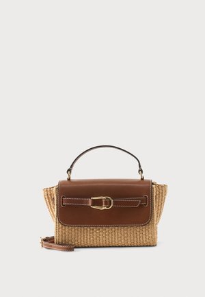 Rektangulær flettet stråhåndtaske med brun læderklap, guldlås, top håndtag og aftagelig skulderrem på hvid baggrund.